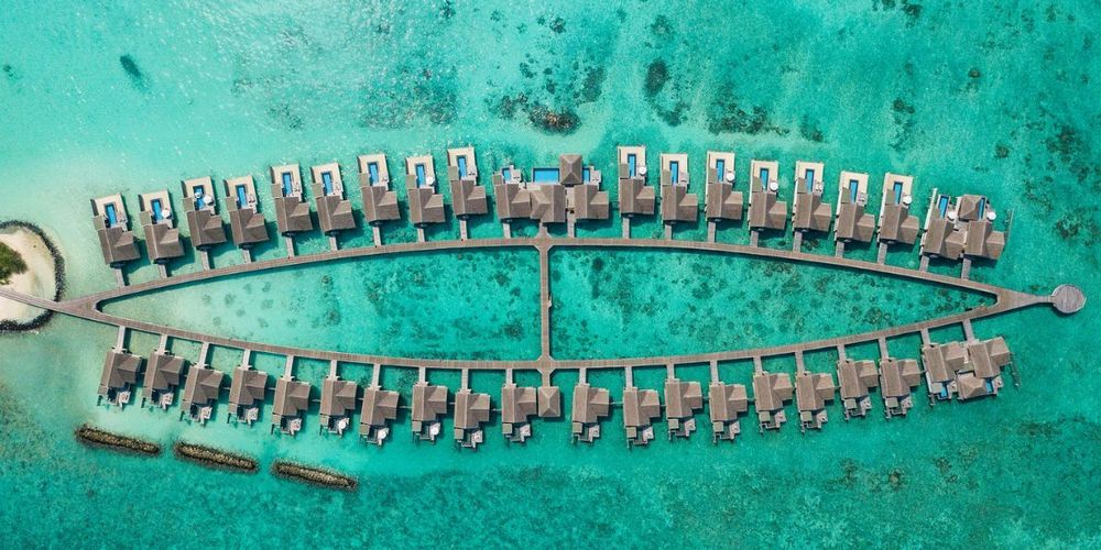 Aerial view of the overwater villas at Sirru Fen Fushi, Maldives, forming a unique eye-shaped pattern over the lagoon
